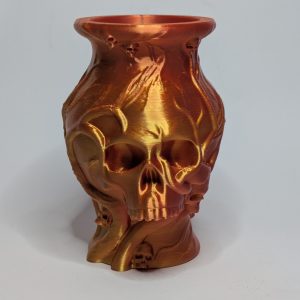 Bronze and gold decorative vase with skull and flame relief design