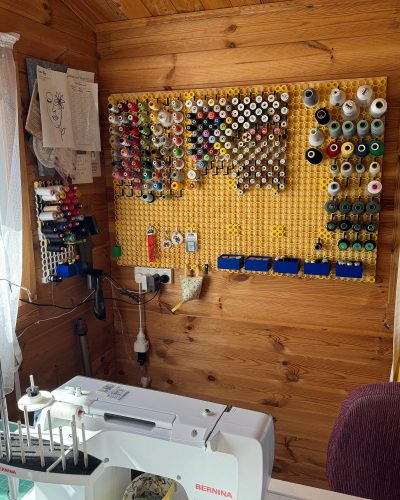 Organized sewing room with multiboard wall storage system displaying thread, scissors, and crafting supplies