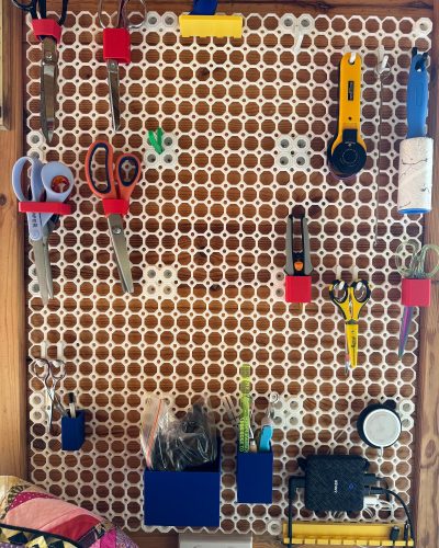 Organized sewing room with multiboard wall storage system displaying thread, tools, and supplies